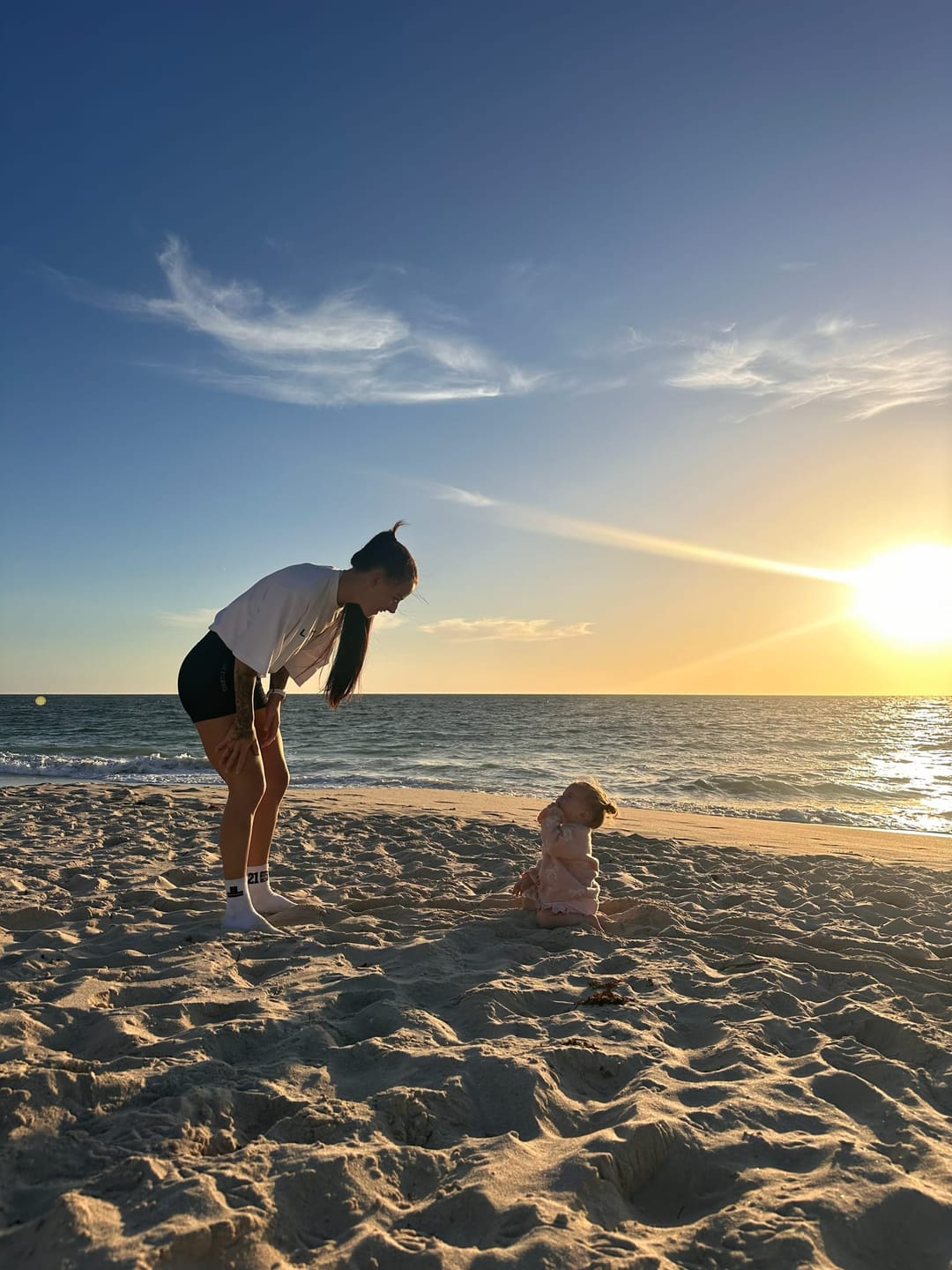 A mum and her young child together on a Perth beach at sunset.