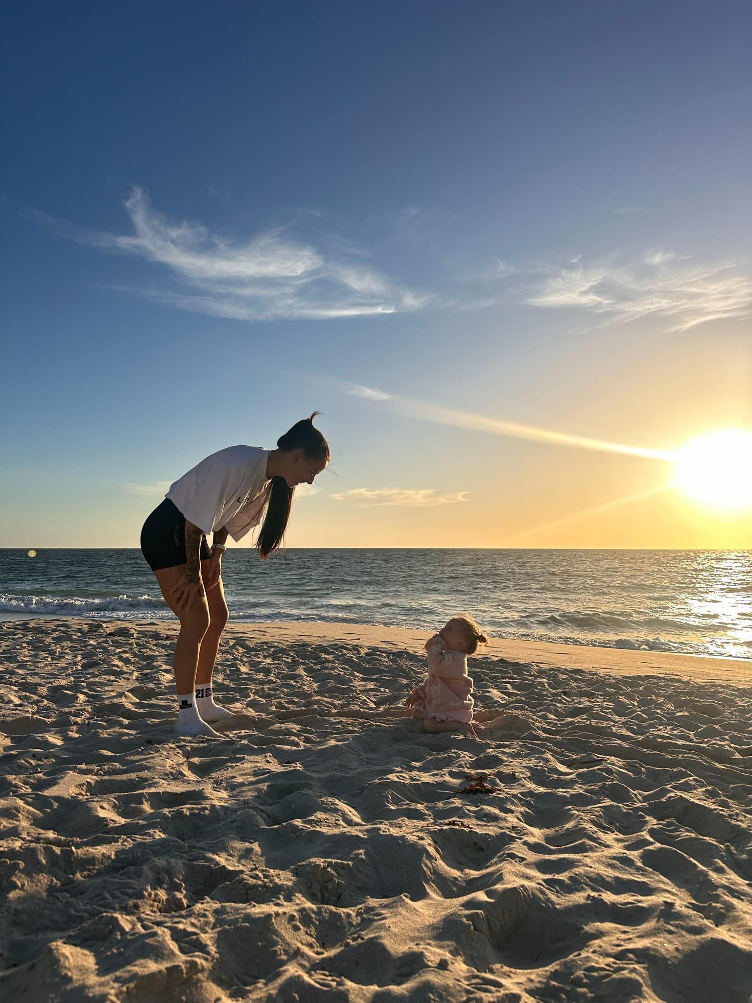 A mum and her young child together on a Perth beach at sunset.